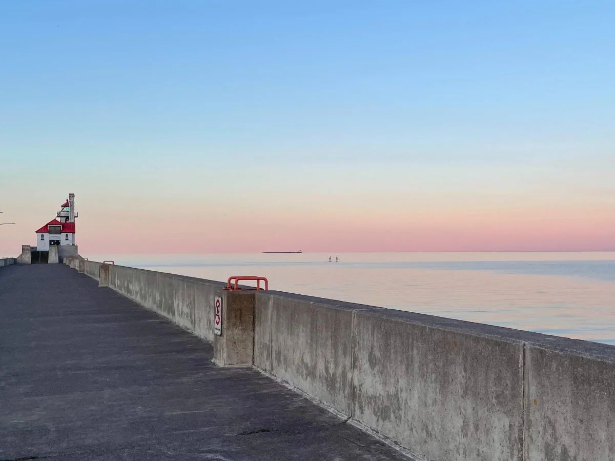 A lighthouse at the end of a pier at sunset